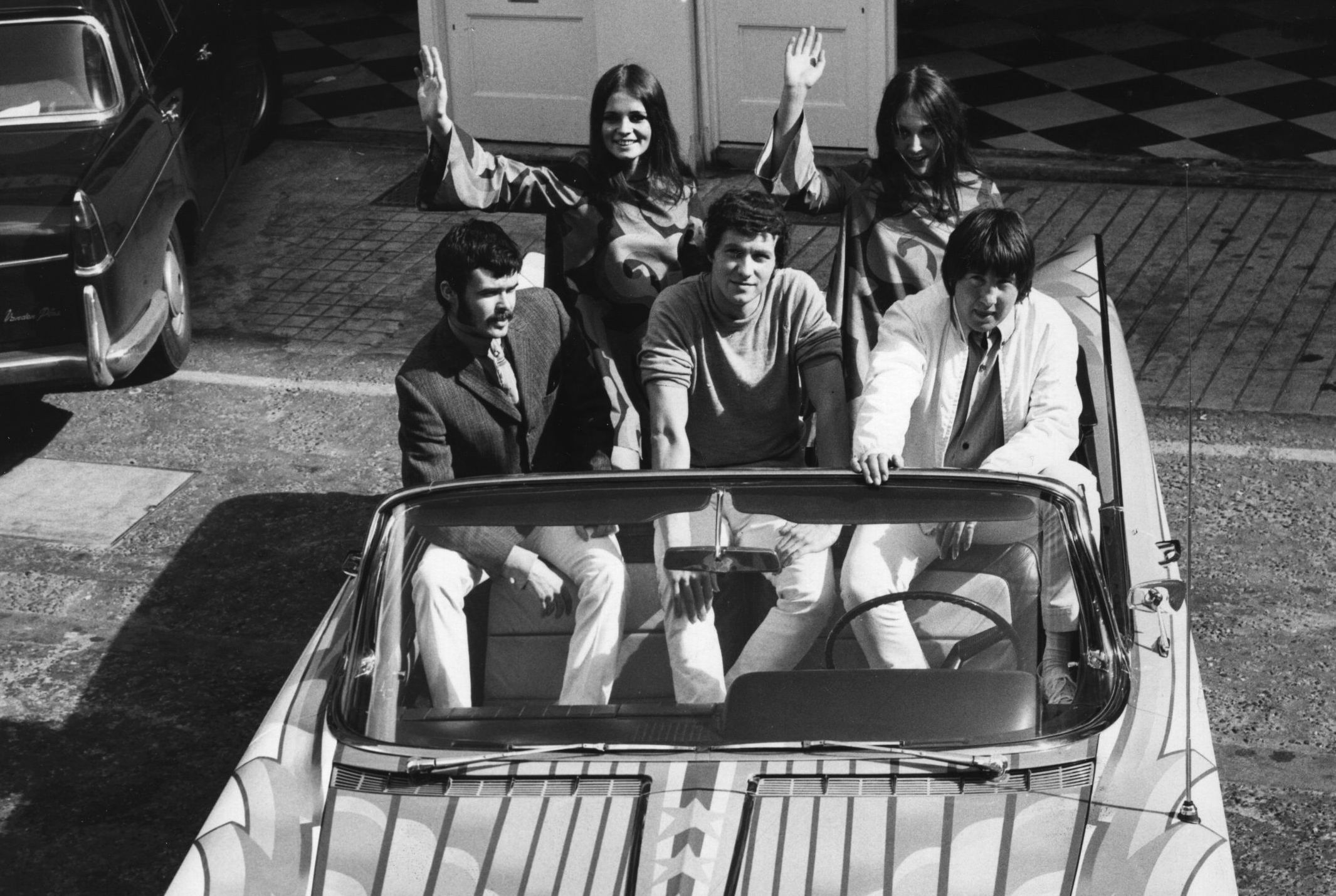 A Buick Electra car which became a work of art at the hands of three young artists who are, (left to right), Douglas Binder, Dudley Edwards and David Vaughan. Douglas and David's wives, Wendy and Mary, can be seen in the back of the car.