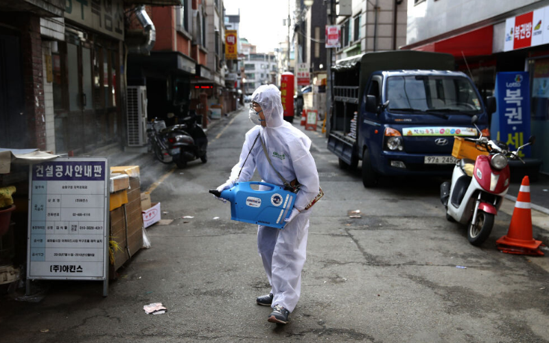 A health professional spray disinfectant on a street in South Korea