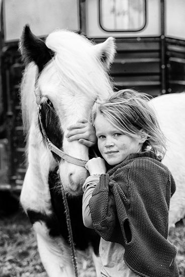 A young Traveller child poses with a horse.