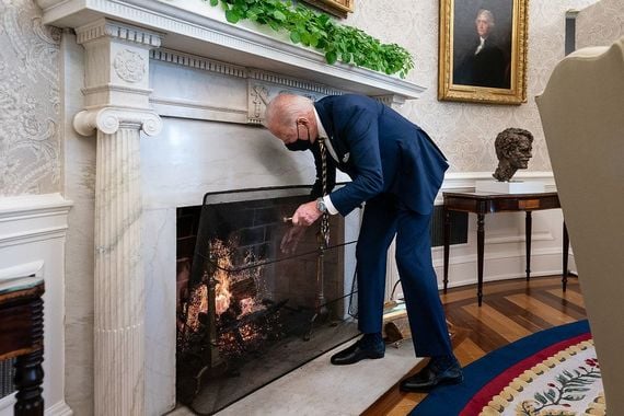 President Joe Biden adds a log to the fire in the Oval Office of the White House. President Joe Biden adds a log to the fire in the Oval Office of the White House.