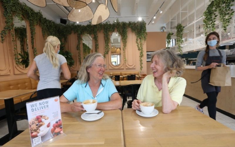 Customers Patricia Bree and Collette Harton having coffee while staff wear face masks at KC Peaches cafe in Dublin. (RollingNews.ie)