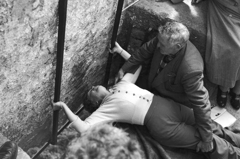 Circa 1950: With the help of the curator of the stone, a woman bends to kiss the Blarney Stone at Blarney Castle in County Cork. (Getty Images)