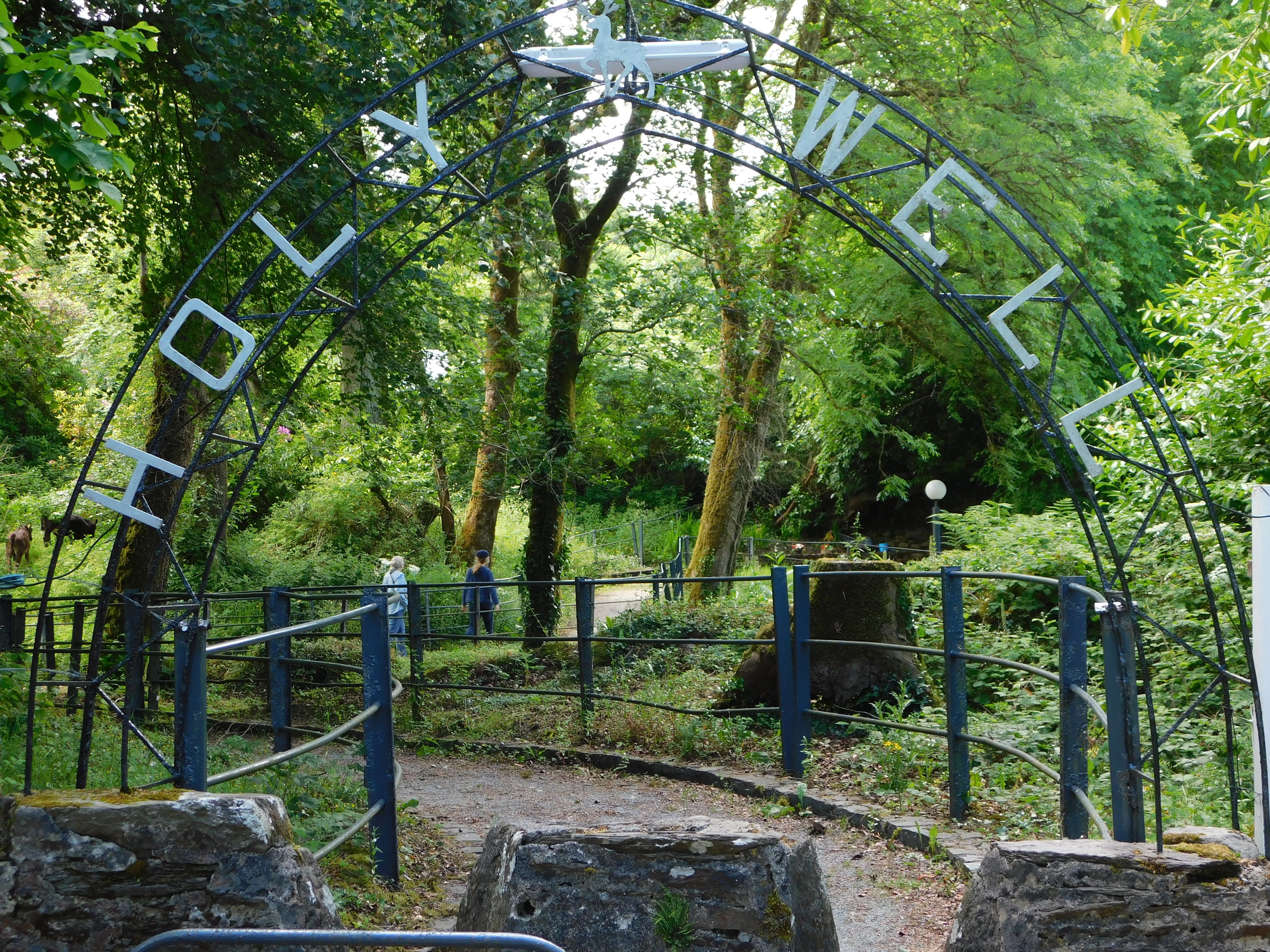 The beautiful and welcoming entrance to St. Gobnait's Holy Well in Ballyvourney, County Cork. This is one of four holy wells named after St. Gobnait who was born in County Clare in the sixth century. The beautiful and welcoming entrance to St. Gobnait's Holy Well in Ballyvourney, County Cork. This is one of four holy wells named after St. Gobnait who was born in County Clare in the sixth century.