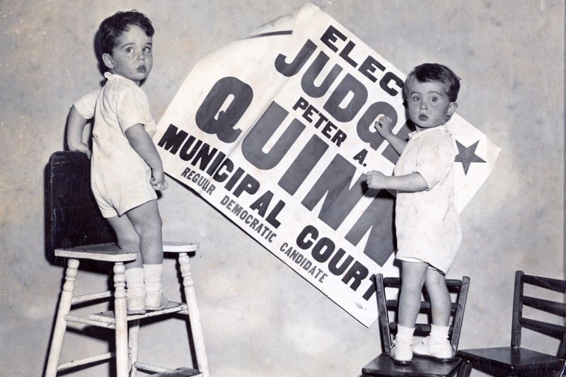 Peter and his brother as small boys hanging their father's campaign poster on the wall.