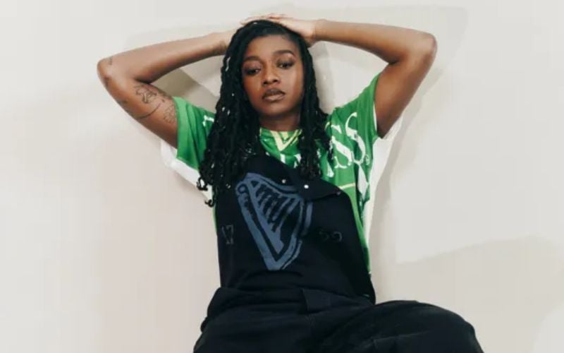 Little Simz wearing the Guinness bottle top print T-shirt, €220 and the Guinness workwear dungarees, €890
