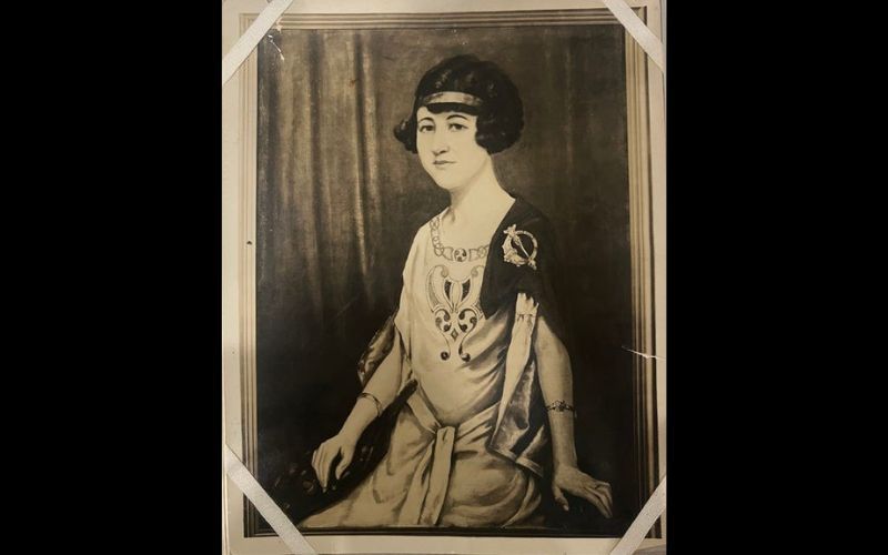 Photograph of a portrait of Josephine Patricia Smith painted in 1927 by Michael M. Loughlin. Loughlin was a painter who also worked in stained-glass, designing the windows of Our Lady Queen of Martyrs Church in Forest Hills. In this portrait, Smith is wearing 17th-century dancing attire, which she copied from a history book, as well as a Tara broach and a claddagh bracelet. The influence of the “flapper era” in which the portrait was painted is evident in Smith's hairstyle.