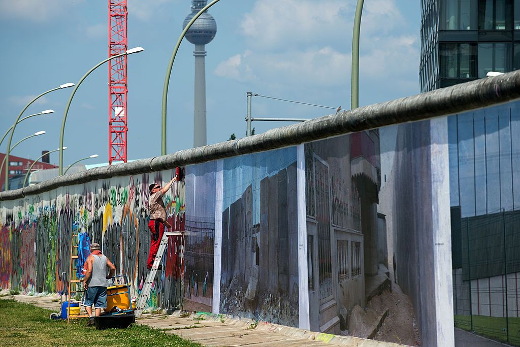 Workers put up panorama pictures of German photographer Kai Wiedenhoefer that are part of his 'Wall on Wall' exhibition on a remaining section of the Berlin Wall in Berlin, Germany on July 9, 2013. Image: JOHANNES EISELE/AFP/Getty Images.
