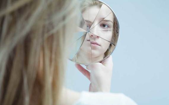 Stock photo of a girl looking into a shattered mirror. Credit: iStock