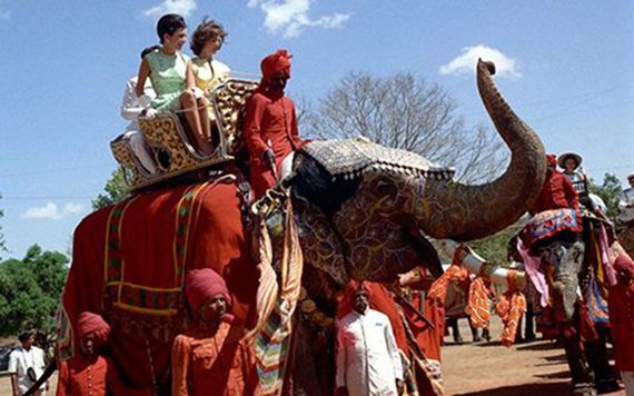 First Lady Jacqueline Kennedy (right) and her sister Princess Lee Radziwill of Poland (left) ride an elephant, Bibia, in the courtyard of Amber Palace in Jaipur, Rajasthan, India. Credit: Public Domain / WikiCommons.