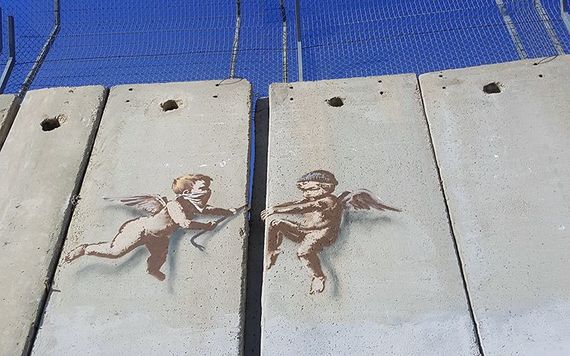 Graffiti of two angels ripping the wall apart along the West Bank border, in Palestine.