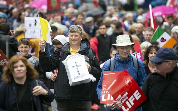 A pro-life march in Dublin: Man holds baby's coffin and Vatican flag.