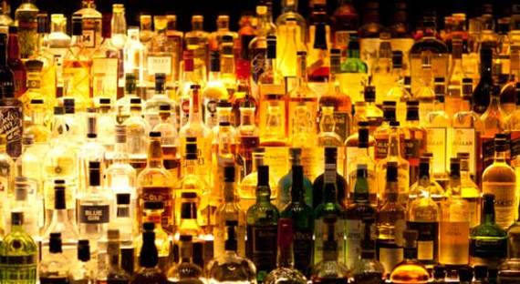 Various liquor bottles backlit behind bar. Various liquor bottles backlit behind bar. Credit: iStock