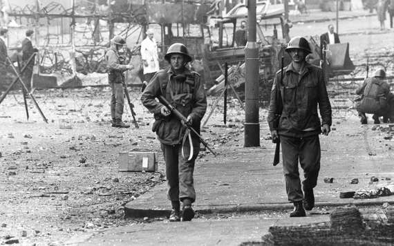 16th August 1969: British soldiers on patrol beside barbed wire defences at the junction of Percy Street and Falls Road in Belfast during unrest in Northern Ireland. (Photo by James Jackson/Evening Standard/Getty Images)